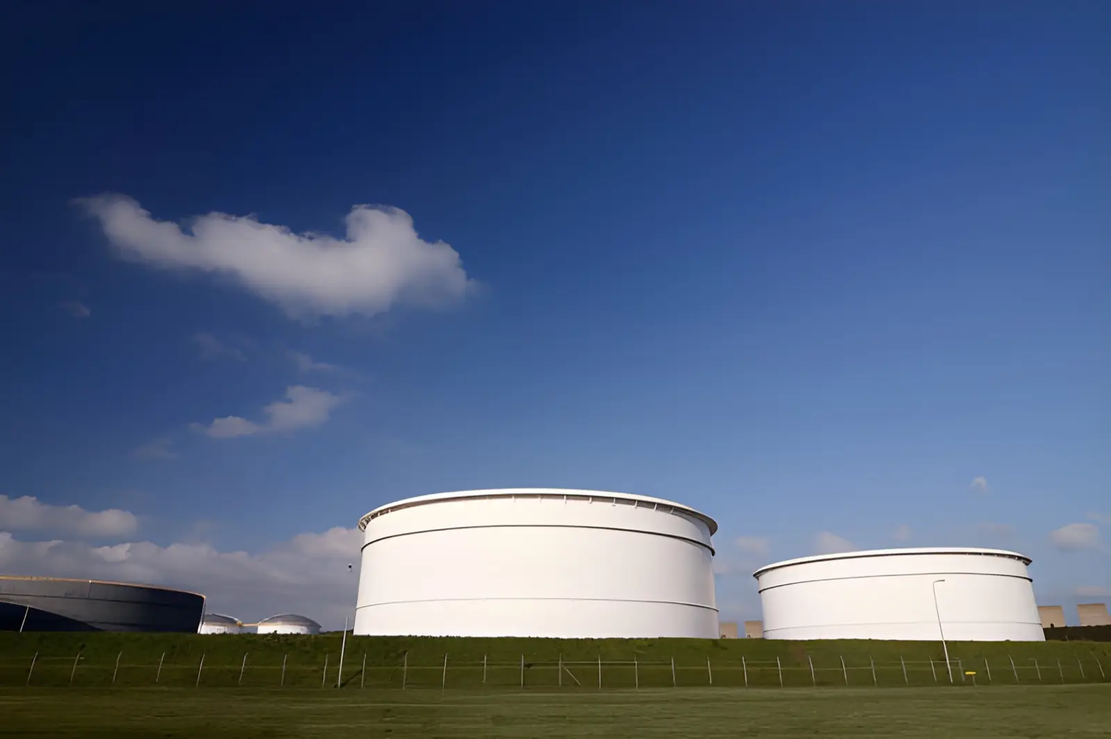 Large petroleum storage tanks at a JSF Logistics terminal under a clear sky