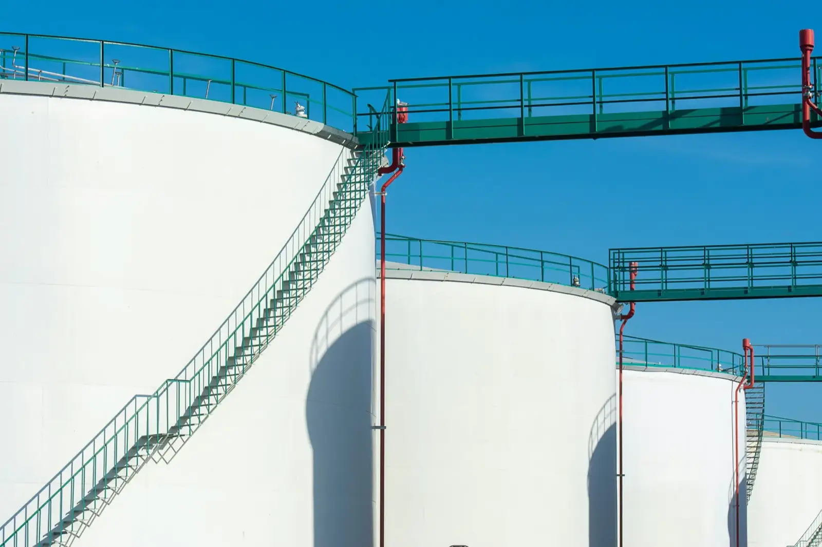 White oil storage tanks with green stairways at a JSF Logistics tank farm terminal